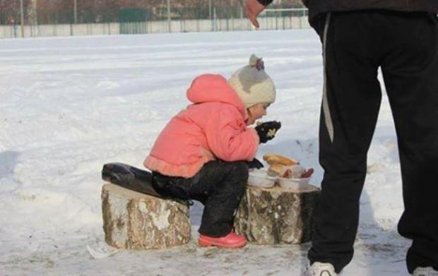 Маленька дівчинка змушена їсти на вулиці в мороз. Фото: соцмережі.