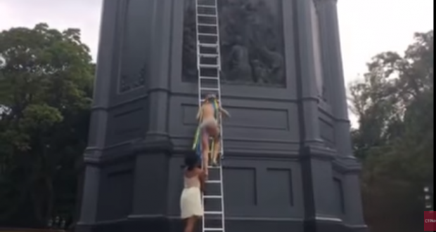 Активістка Femen залізла на пам'ятник. Фото: скріншот з відео.