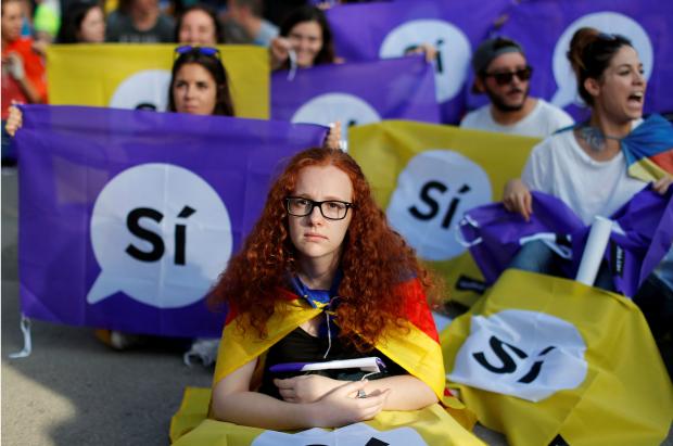 Люди спостерігають за засіданням каталонського регіонального парламенту, сидячи перед гігантським екраном на мітингу в підтримку незалежності в Барселоні. Фото:atlanticcouncil.org