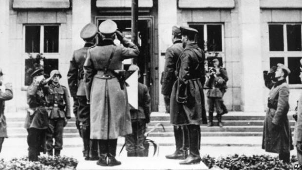 Німецькі та російські офіцери салютують нацистському прапору зі свастикою під час параду в Брест-Литовську, який відзначає демаркацію кордону Польщі. 22 вересня 1939 року