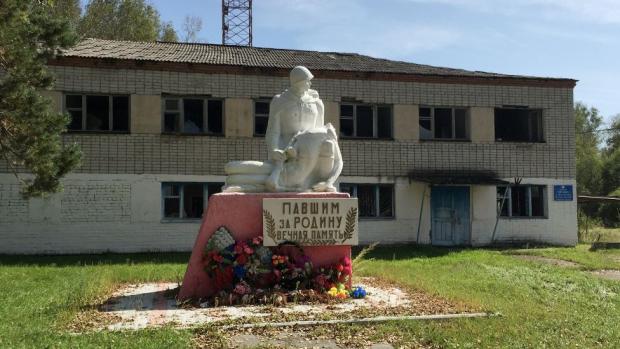 За памятником погибшим в Великой Отечественной войне - заброшенное здание, в котором находилось правление колхоза "Маяк"