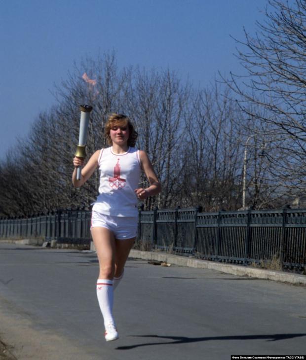 Жінка біжить з олімпійським факелом перед відкриттям Ігор