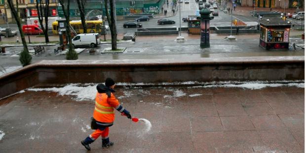 Працівник комунальної служби посипає дорогу сіллю, Київ