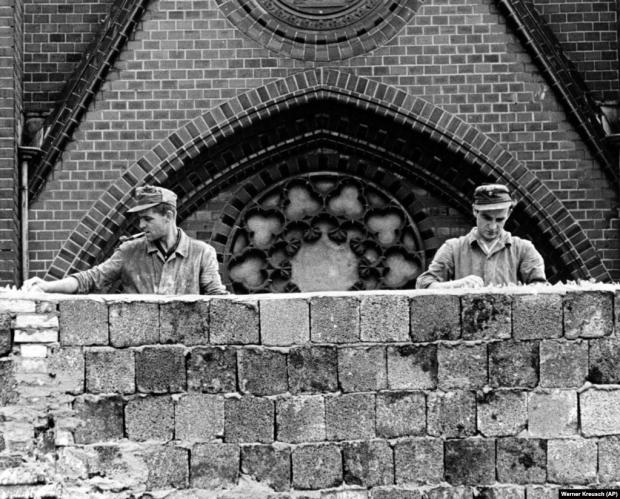 Двоє східнонімецьких робітників вкладають (вмуровують) бите скло на верхівку 15-метрової стіни, щоб запобігти спробам втечі берлінців із НДР до ФРН. Берлін, 22 серпня 1961 року