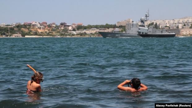 Отдыхающие на фоне российского военного корабля. Севастополь, 2019 год