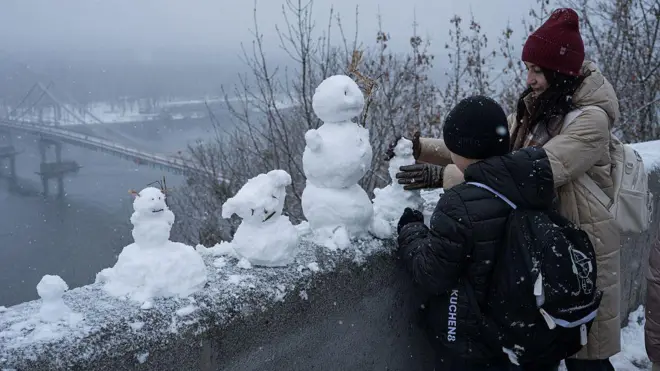 Жінка та дитина ліплять сніговика на оглядовому майданчику в парку Хрещатик