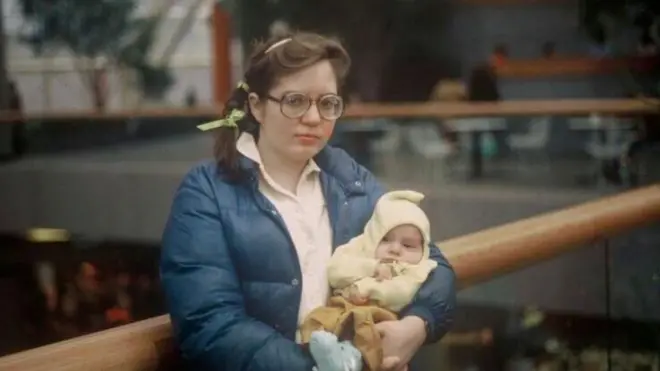 Патрія Лінн Лейн тримає дочку на руках, а її чоловік, Марк Тімоті Герні, фотографує її 