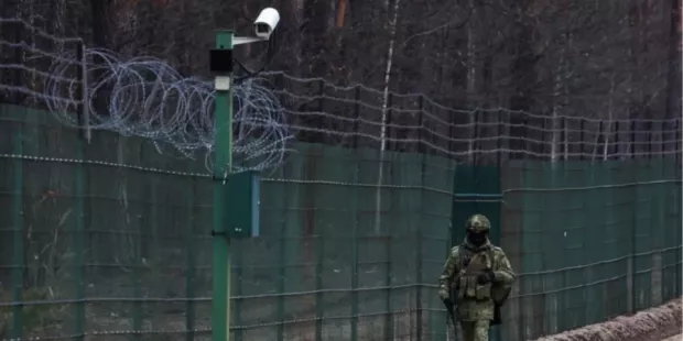 Білоруський прикордонник біля обладнаного камерами паркану з колючим дротом на кордоні з Україною (Фото: Reuters)
